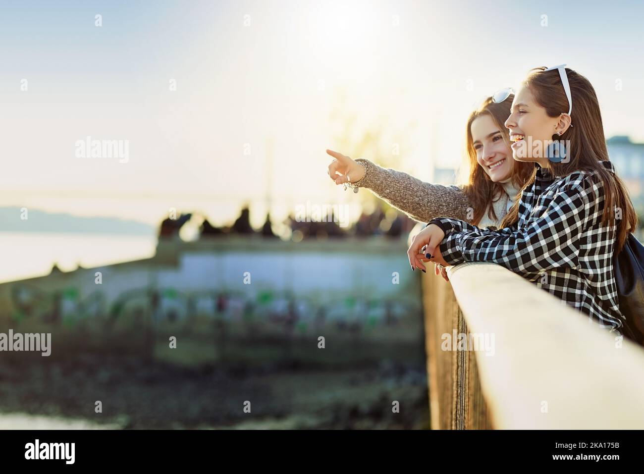 Eine attraktive junge Frau, die ihrem Freund etwas zeigt, während sie auf einem Aussichtspunkt steht. Stockfoto