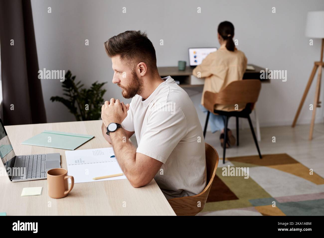 Seitenansicht eines ernsthaften Studenten oder Freiberuflers, der am Arbeitsplatz vor dem Laptop sitzt und während des Online-Unterrichts auf den Bildschirm schaut Stockfoto