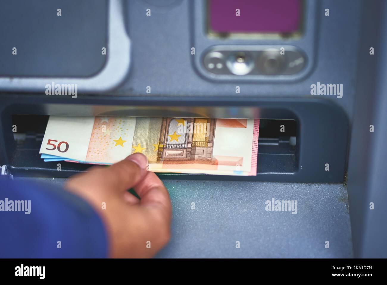 Die erste Station am Zahltag. Eine Frau, die Geld von einem Geldautomaten abzieht. Stockfoto