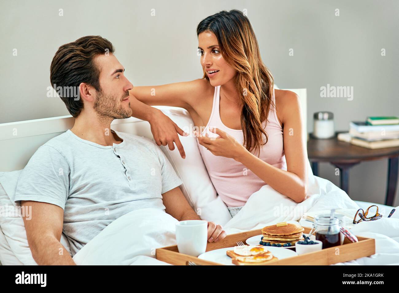 Gönnen Sie sich einen gemütlichen Morgen im Bett. Ein glückliches junges Paar genießt das Frühstück im Bett zusammen zu Hause. Stockfoto