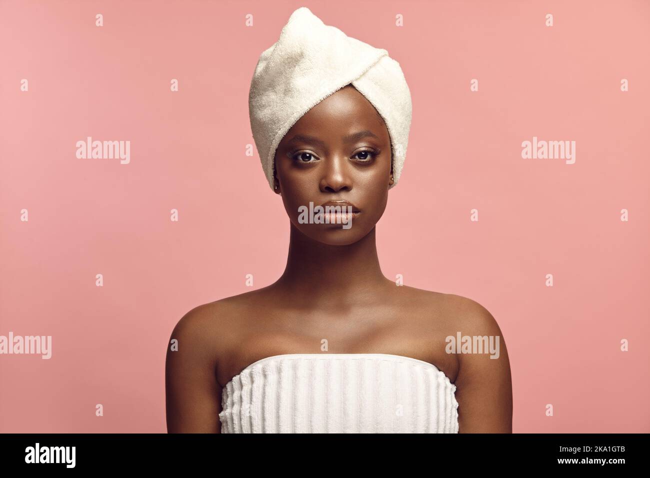 Kopfschuss Porträt von schönen schwarzen Haut Frau in Spa-Handtuch auf einem rosa Hintergrund mit einem freien Kopieplatz. Stockfoto