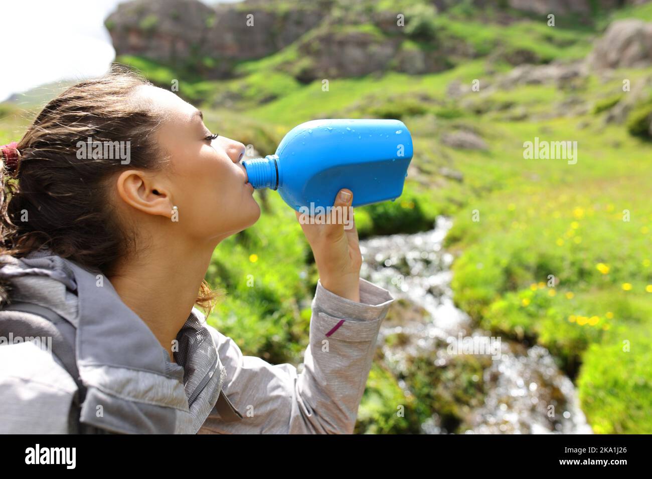 Trekker Trinkwasser aus der Kantine neben einem Bach im Berg Stockfoto