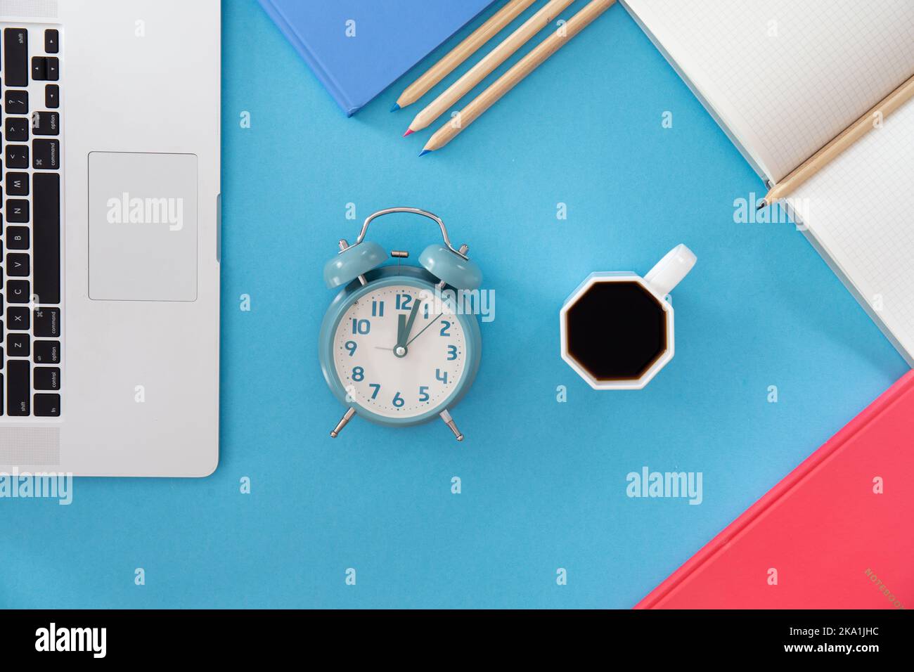 Flach liegend, Wecker und eine Tasse Kaffee am Arbeitsplatz. Stockfoto