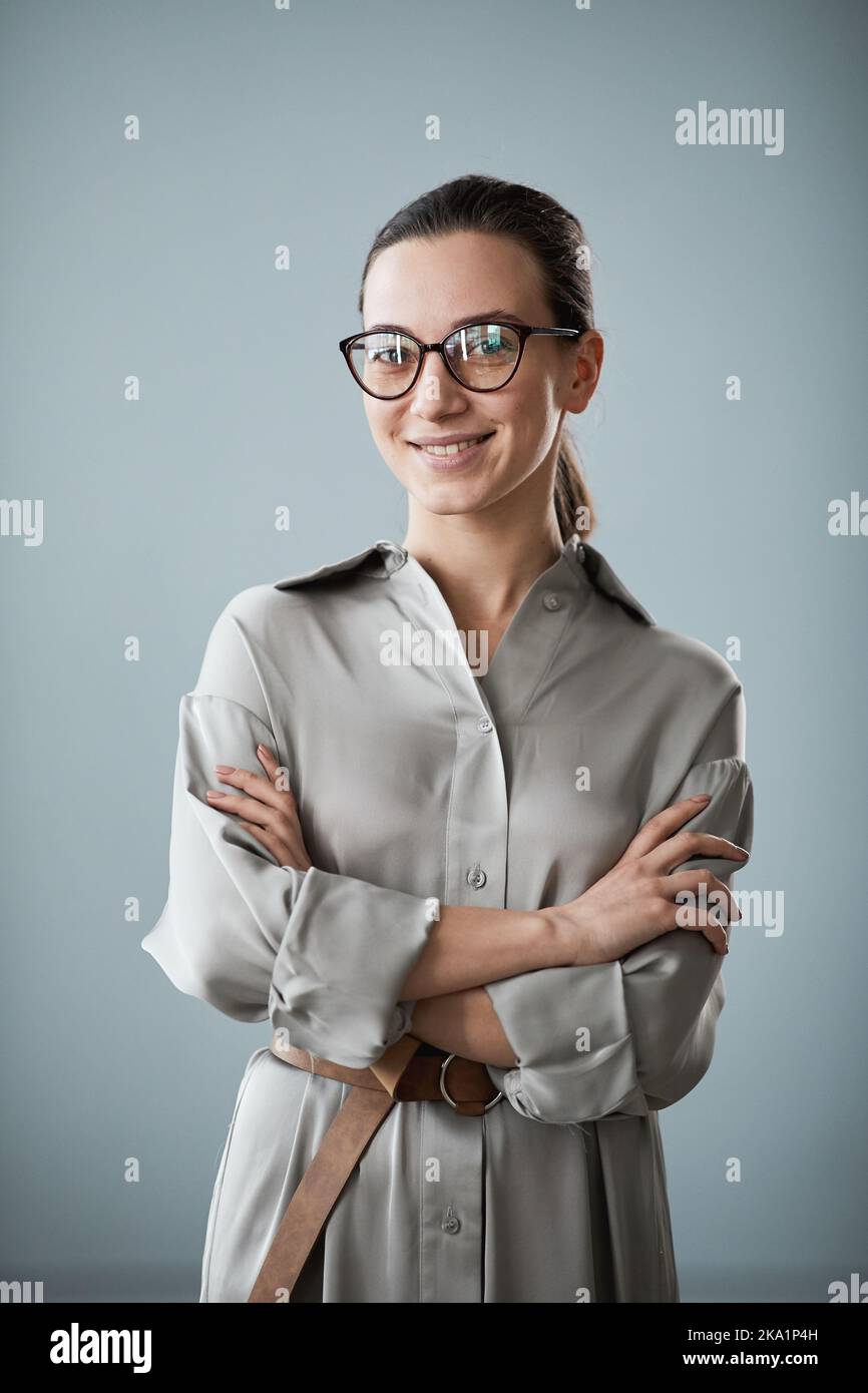 Junge elegante Geschäftsfrau oder Lehrerin in Brillen und smarter Casualwear, die die Kamera betrachtet, während sie isoliert steht Stockfoto