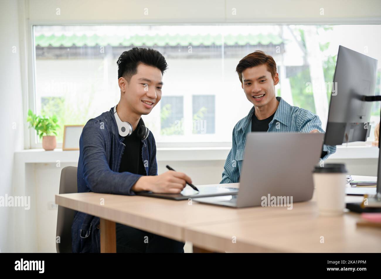 Zwei professionelle junge asiatische Programmierer oder Fotoredakteure arbeiten im Büro zusammen, diskutieren und Brainstorming. Stockfoto