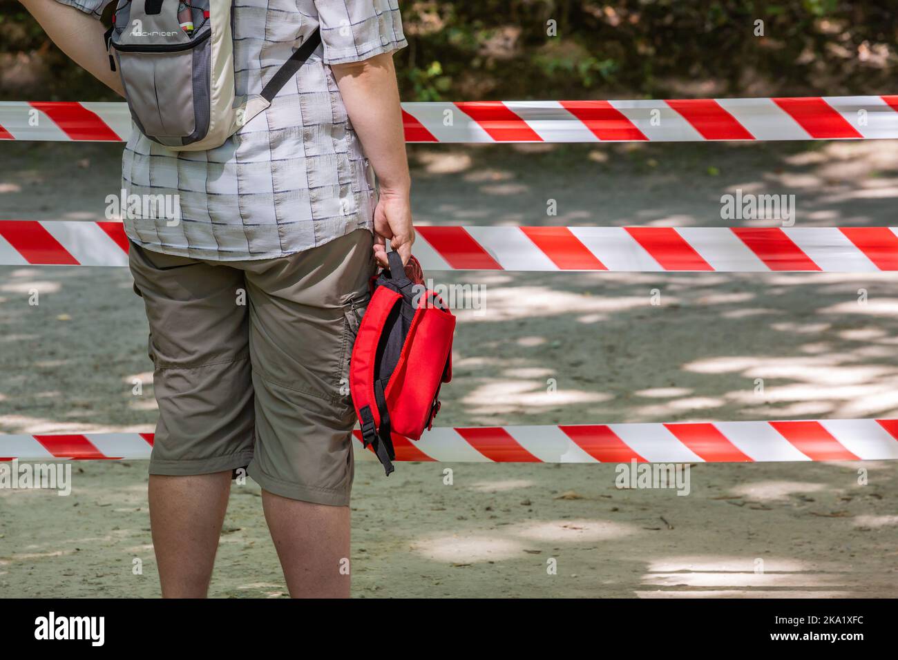 Mann mit roter Tasche vor roten und weißen Sicherheitsleinen. Brüssel. Stockfoto