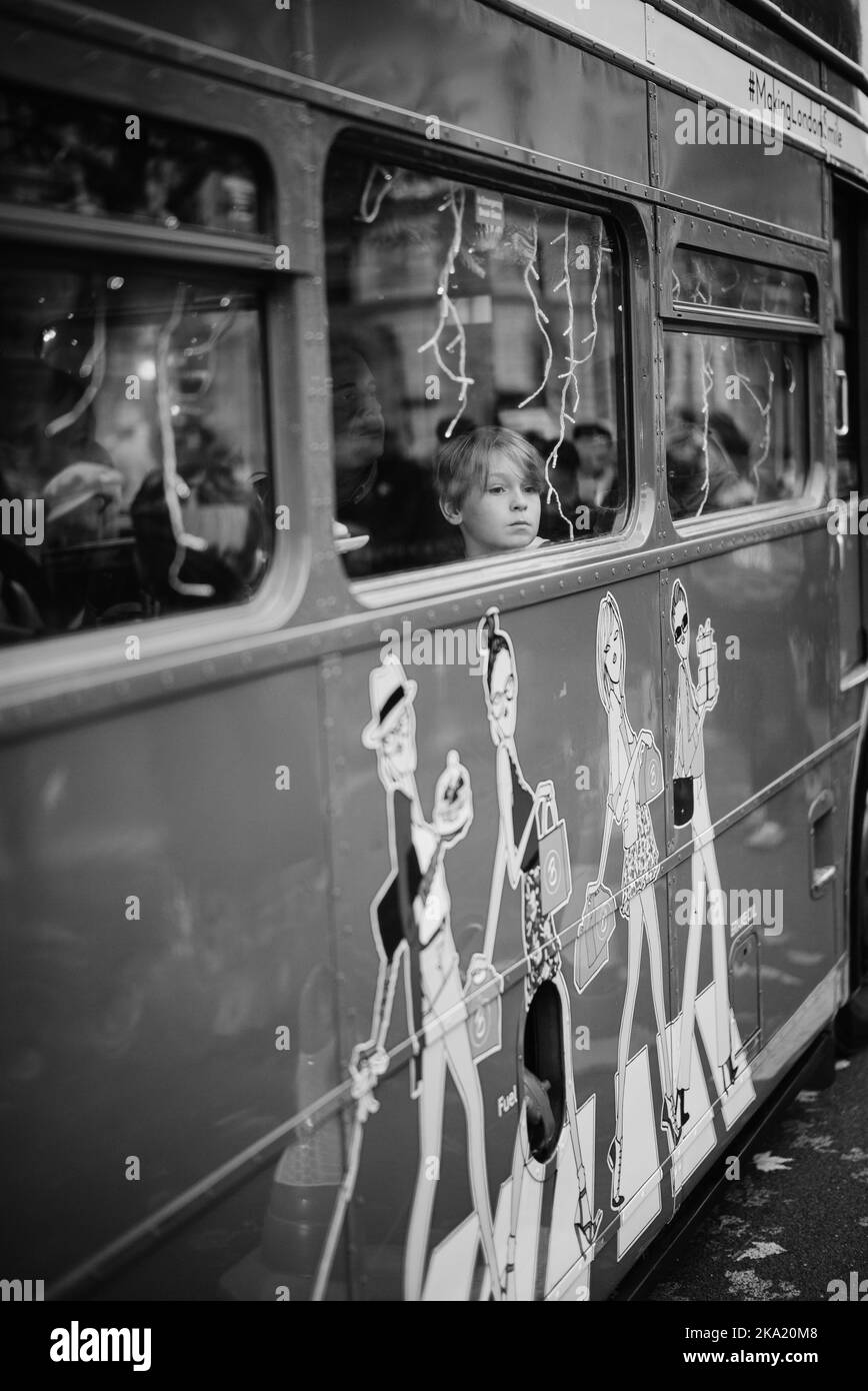 Der Junge schaut aus einem geschmückten Bus in London. Stockfoto