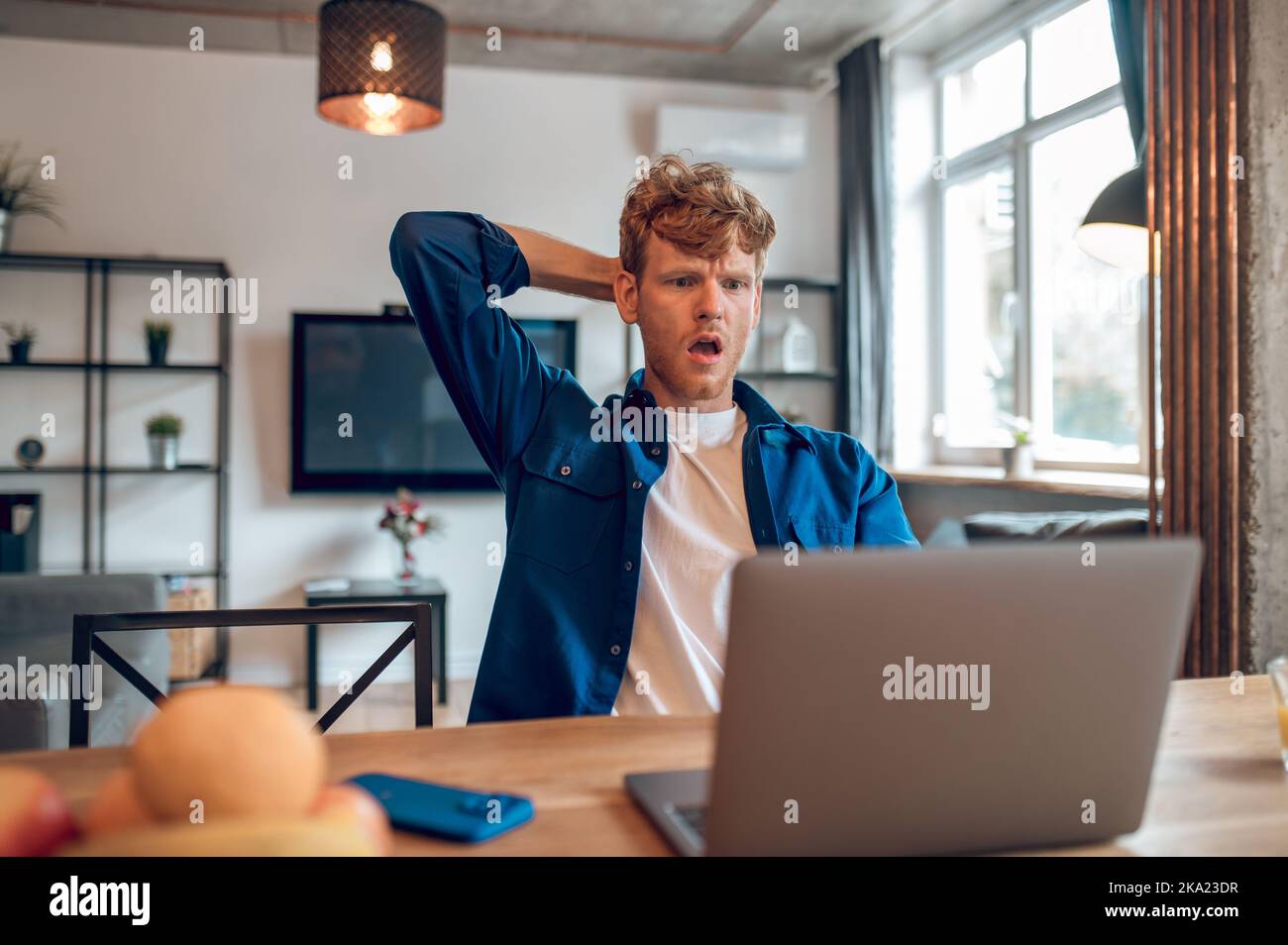 Ingwer-Mann liest etwas online und sieht schockiert aus Stockfoto