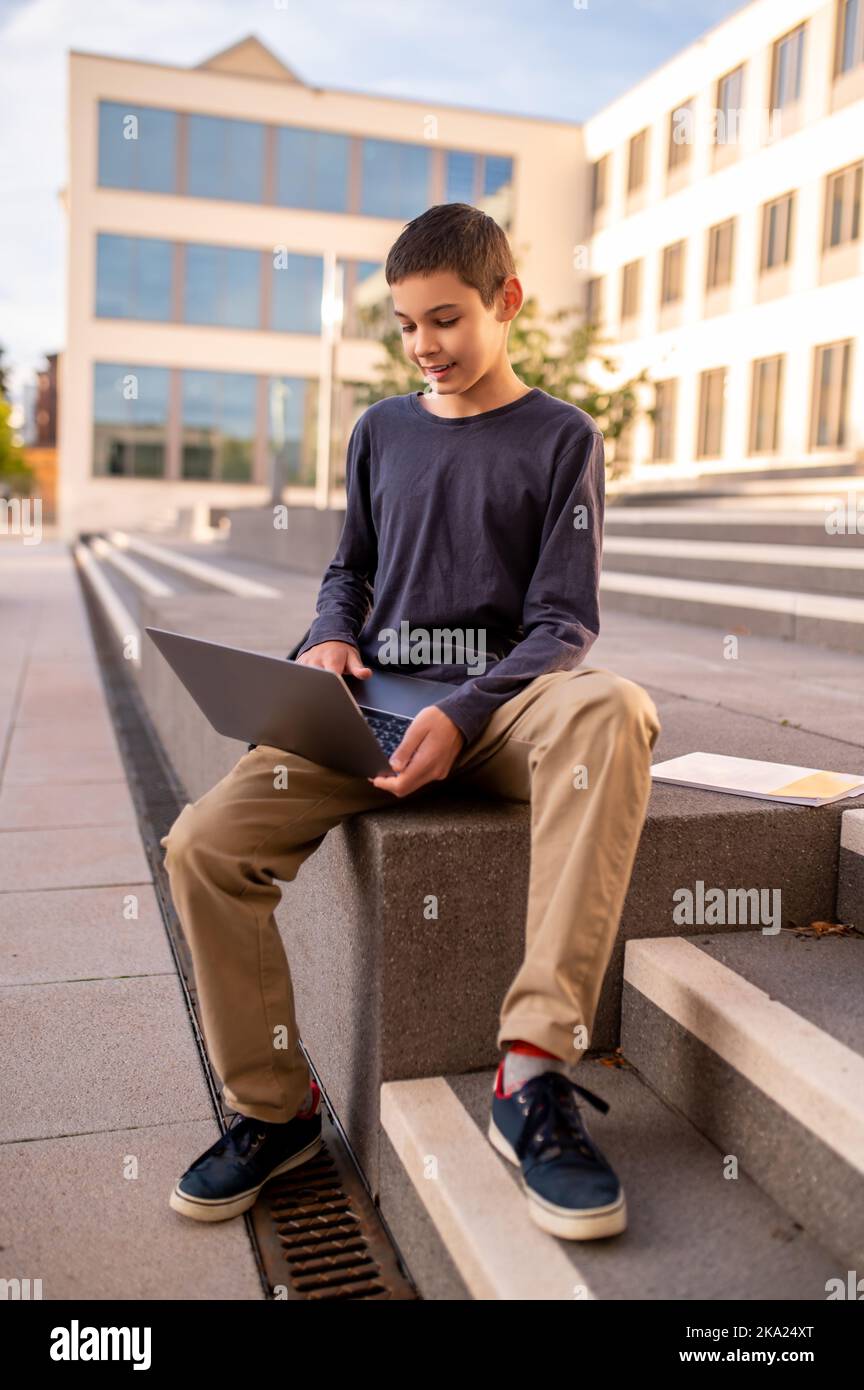 Konzentrierter Teenager, der draußen an seinem tragbaren Computer arbeitet Stockfoto