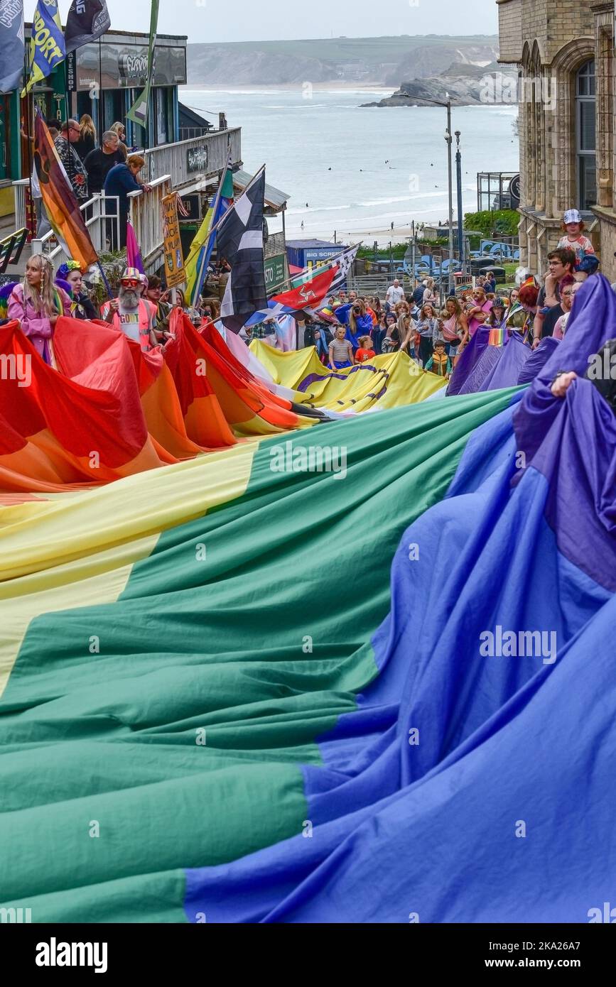 Das farbenfrohe Cornwall ist stolz auf das Banner der Pride-Flagge, das von den Teilnehmern der Parade im Zentrum von Newquay in Großbritannien gehalten wird. Stockfoto
