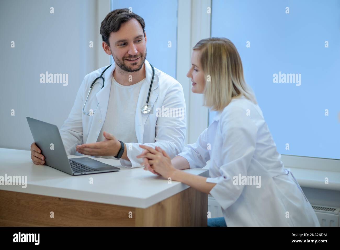 Zwei Ärzte sitzen dicht und diskutieren etwas Stockfoto