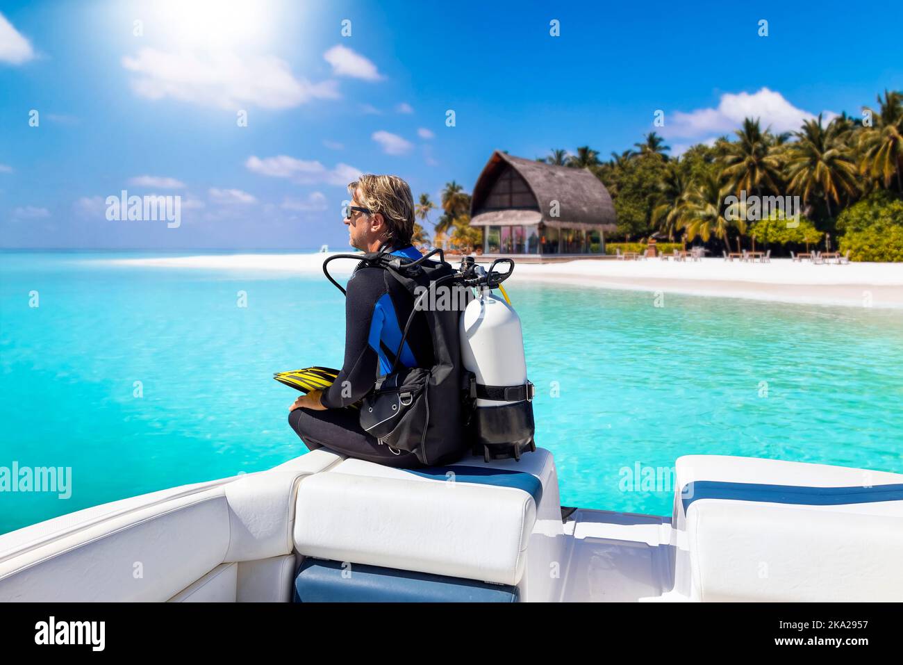 Ein Taucher in seiner Tauchausrüstung sitzt vor einem Boot Stockfoto