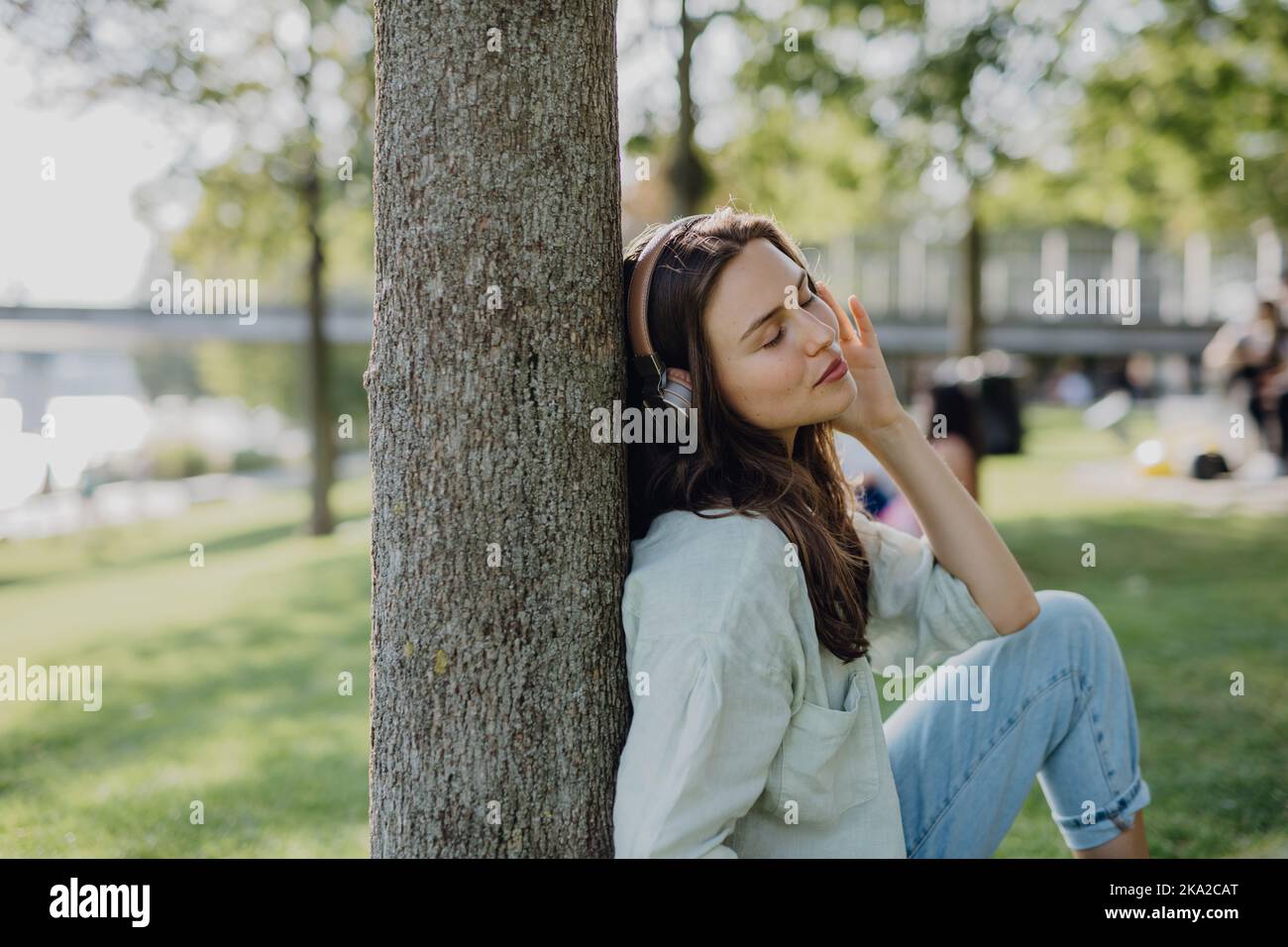 Porträt einer jungen Frau, die im Stadtpark über Kopfhörer Musik hört. Stockfoto