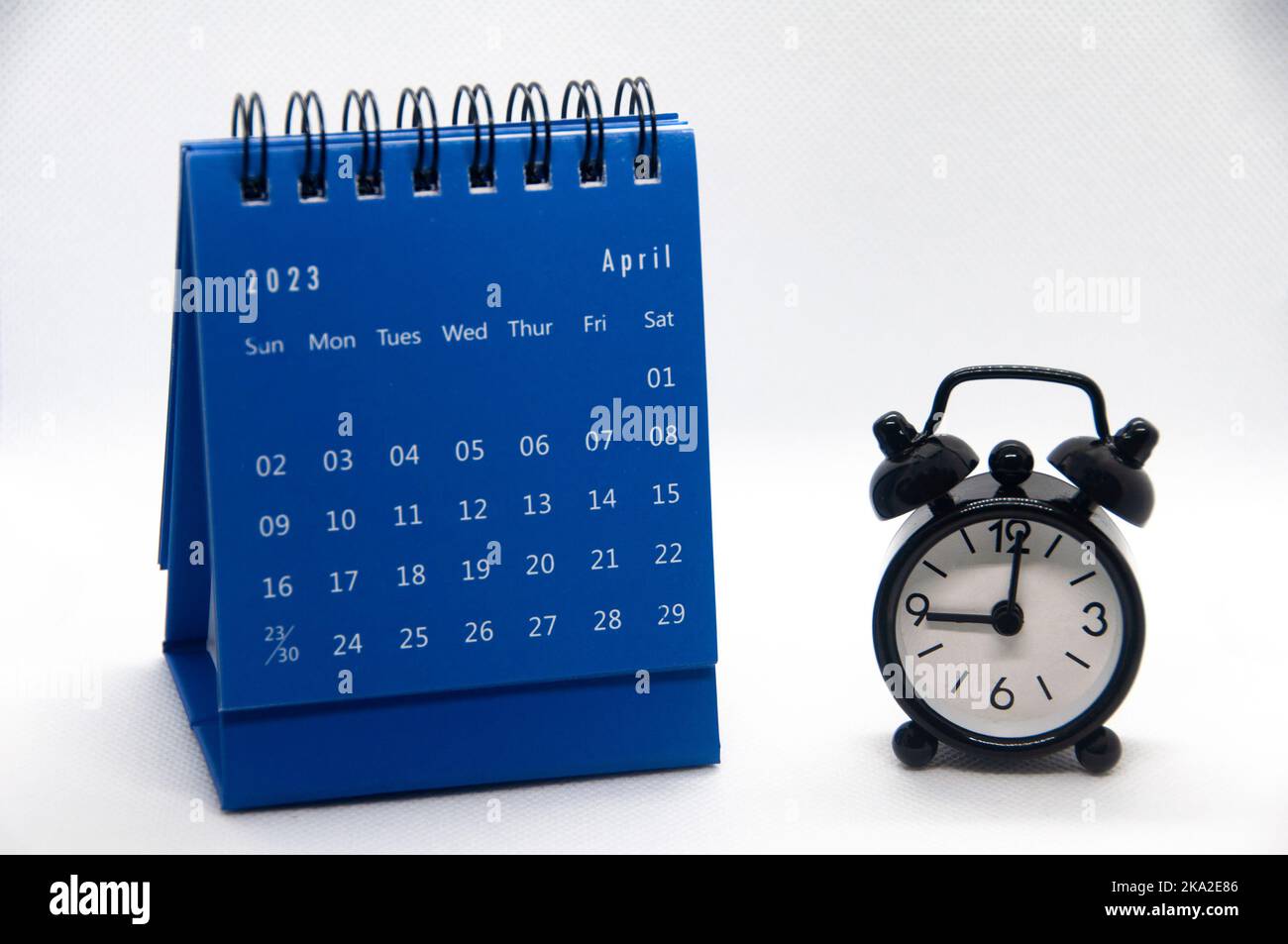 Wecker zeigt auf 9 Uhr mit Kalender vom 2023. April auf weißem 