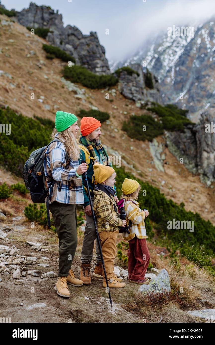 Seitenansicht der Familie mit kleinen Kindern in den herbstlichen Bergen. Konzept eines gesunden Lebensstils. Stockfoto