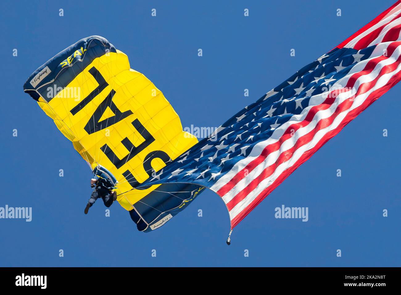 Ein Mitglied des Fallschirmsprungteams der US Navy Leap Frogs bringt die amerikanische Flagge zur Miramar Airshow 2022 in San Diego, Kalifornien. Stockfoto