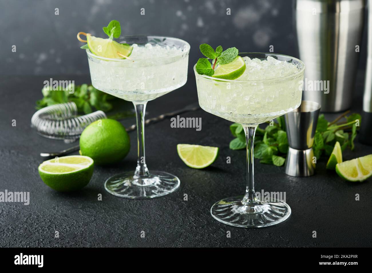Margarita Cocktail mit Limette, Tequila, Minze und Eis auf dunklem Tisch mit erstaunlicher Hintergrundbeleuchtung, Kopierraum. Klassischer Margarita- oder Daiquiry-Cocktail. Barkarte Stockfoto
