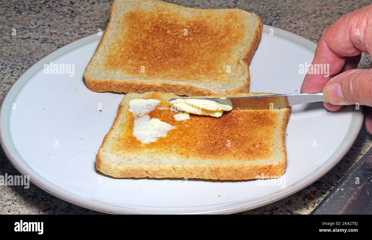 Toast zum Frühstück auf einem Teller buttern. Stockfoto