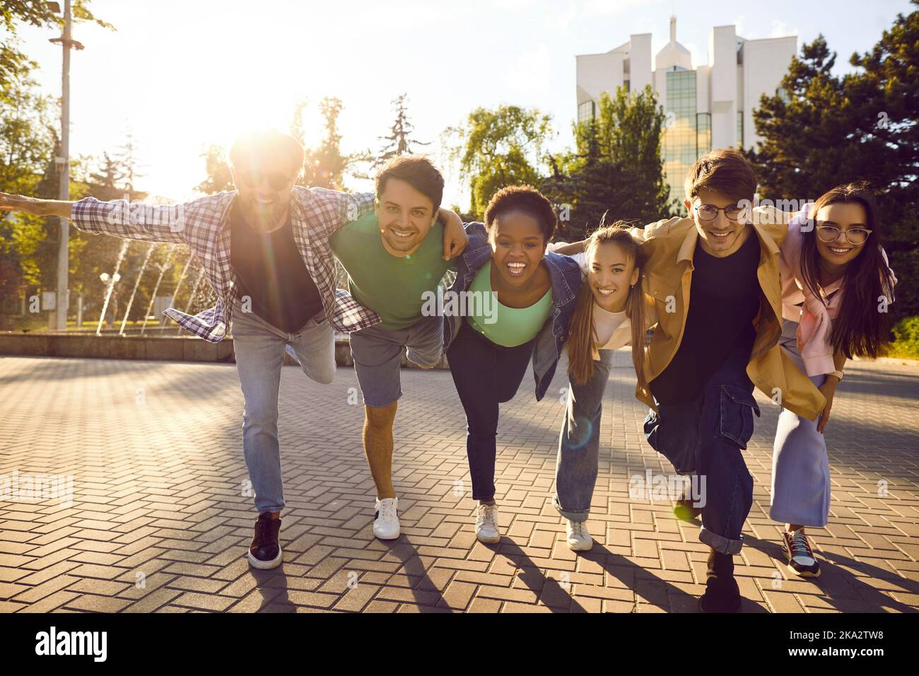 Fröhliche positive multirassische weibliche und männliche Freunde haben Spaß beim Spaziergang durch die Straßen der Stadt. Stockfoto
