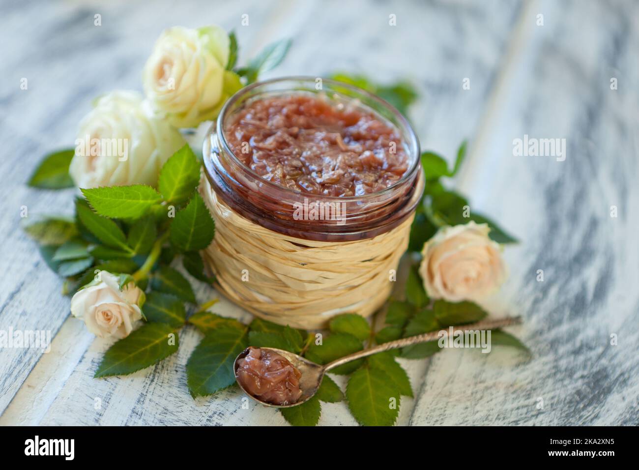 Rosafarbene Marmelade mit Rosenblüten-rosafarbene Blütenblattkonfitüre in einem Glasglas auf neutralgrauem Küchentisch mit Kopierfläche Stockfoto