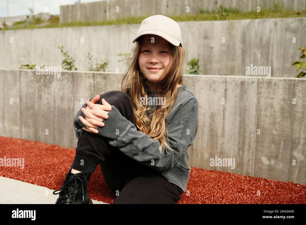 Nettes Mädchen auf Schotterboden sitzend Stockfoto