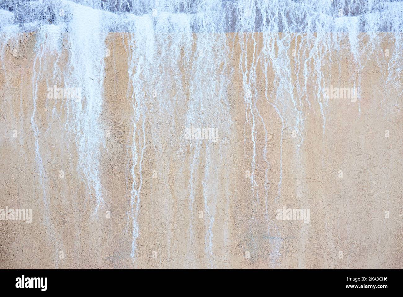 Alte Betonwand stuckblau und beige sandig mit salzenden Tropfen Flecken wie Wasserfall. Stockfoto