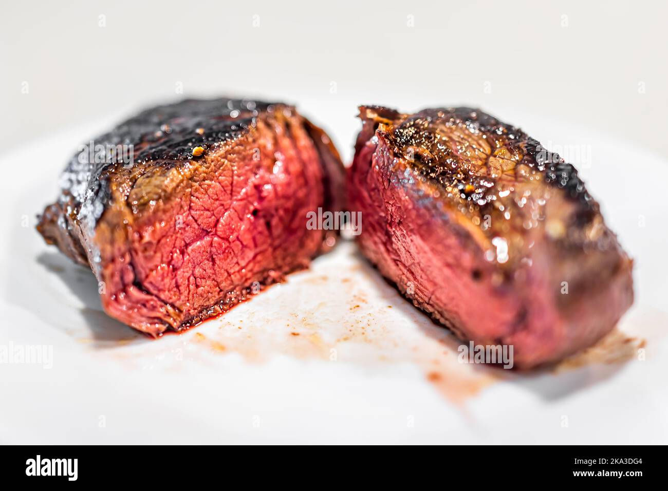 Makro-Nahaufnahme von gekochtem, seltenem blauroten, rohen Petite Sirloin-Steak, innen auf weißem Teller auf dem Tisch isoliert vor weißem Hintergrund geschnitten Stockfoto