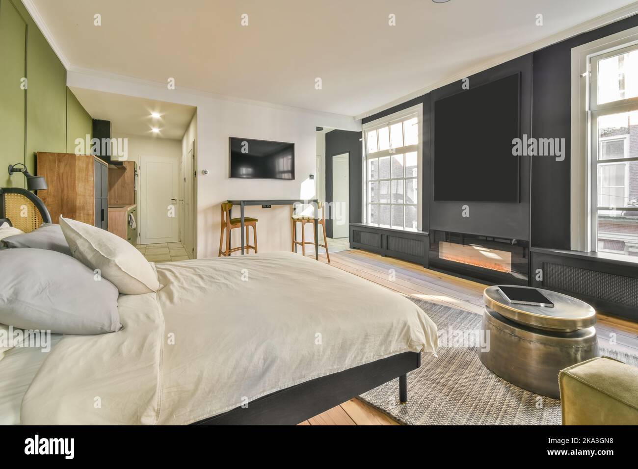 Moderner Fernseher vor einem bequemen weichen Bett im geräumigen Schlafzimmer Stockfoto
