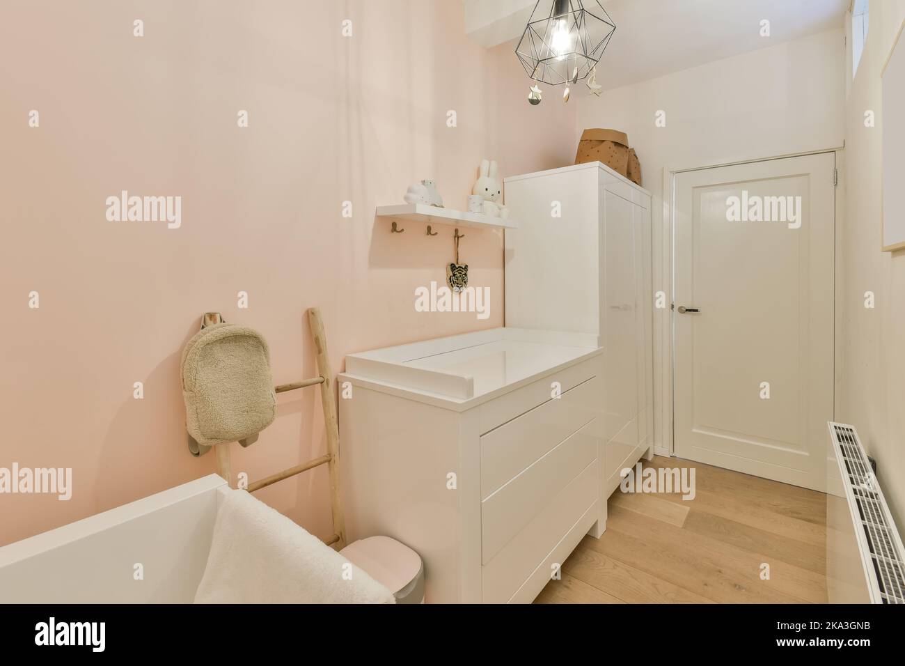 Weißes Holzkrippe mit weißer Matratze an der Wand im hellen Kinderzimmer zu Hause platziert Stockfoto