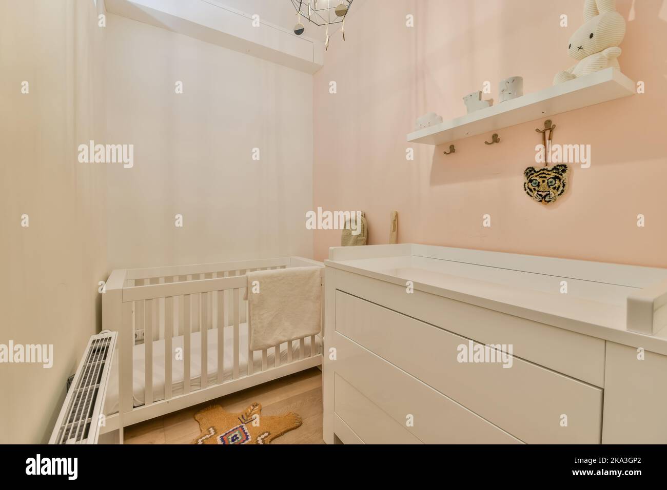 Weißes Holzkrippe mit weißer Matratze an der Wand im hellen Kinderzimmer zu Hause platziert Stockfoto