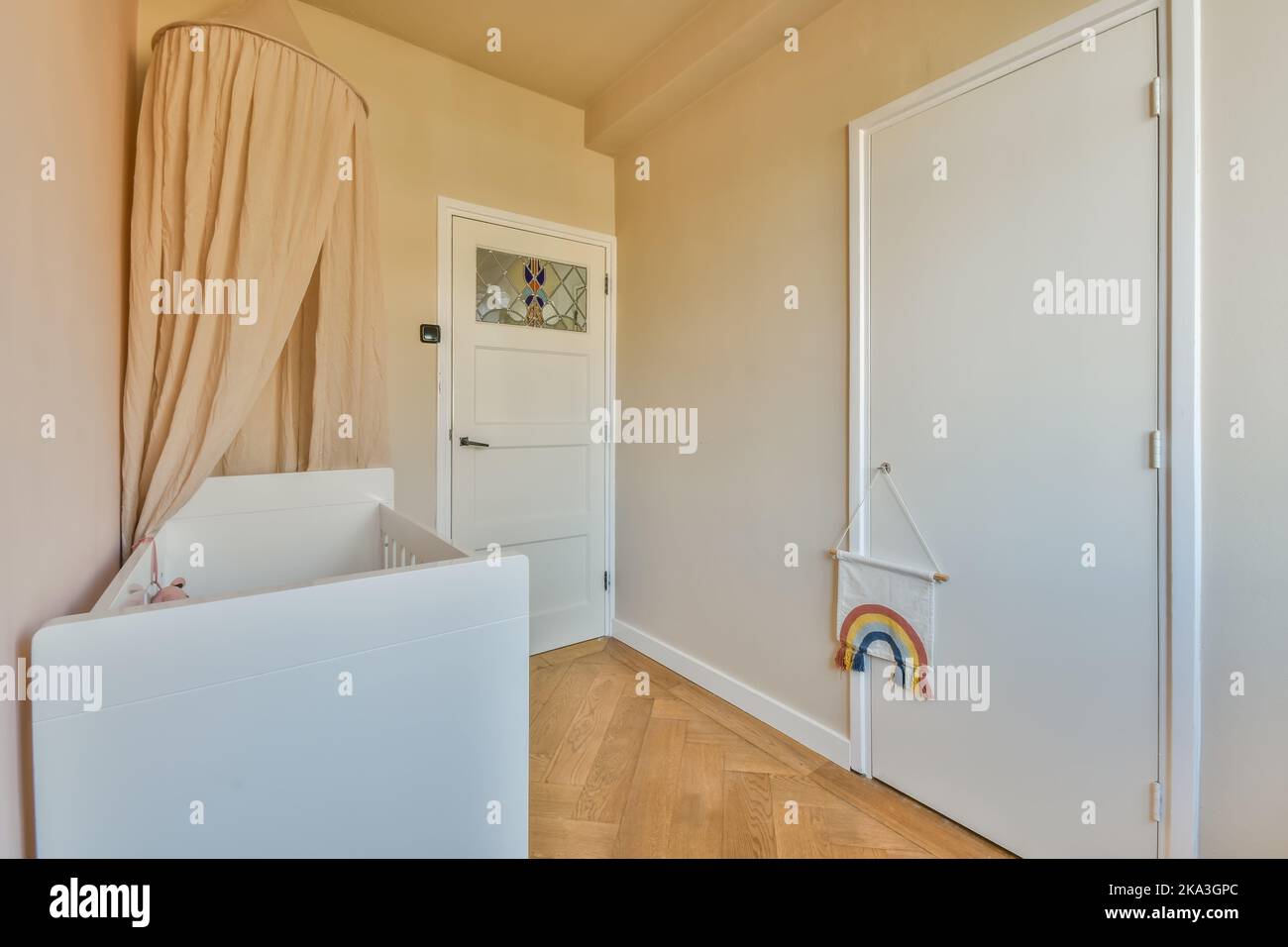 Weißes Holzkrippe mit weißer Matratze an der Wand im hellen Kinderzimmer zu Hause platziert Stockfoto
