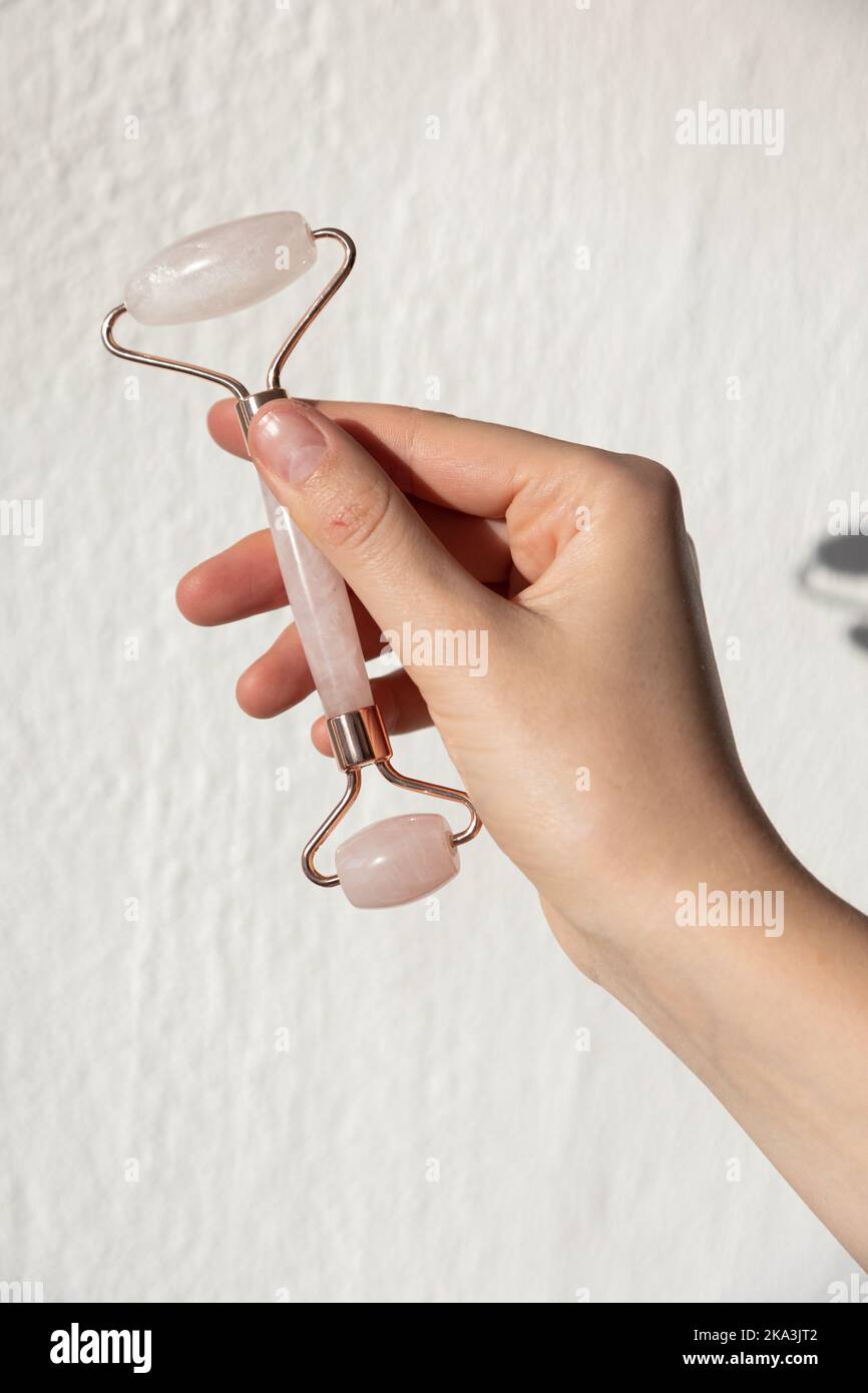 Gesichtswalze aus Steinjade und Massagegerät aus Gua Sha Rosenquarz. Gesichtspflege und Anti-Age-Produkte. Stockfoto