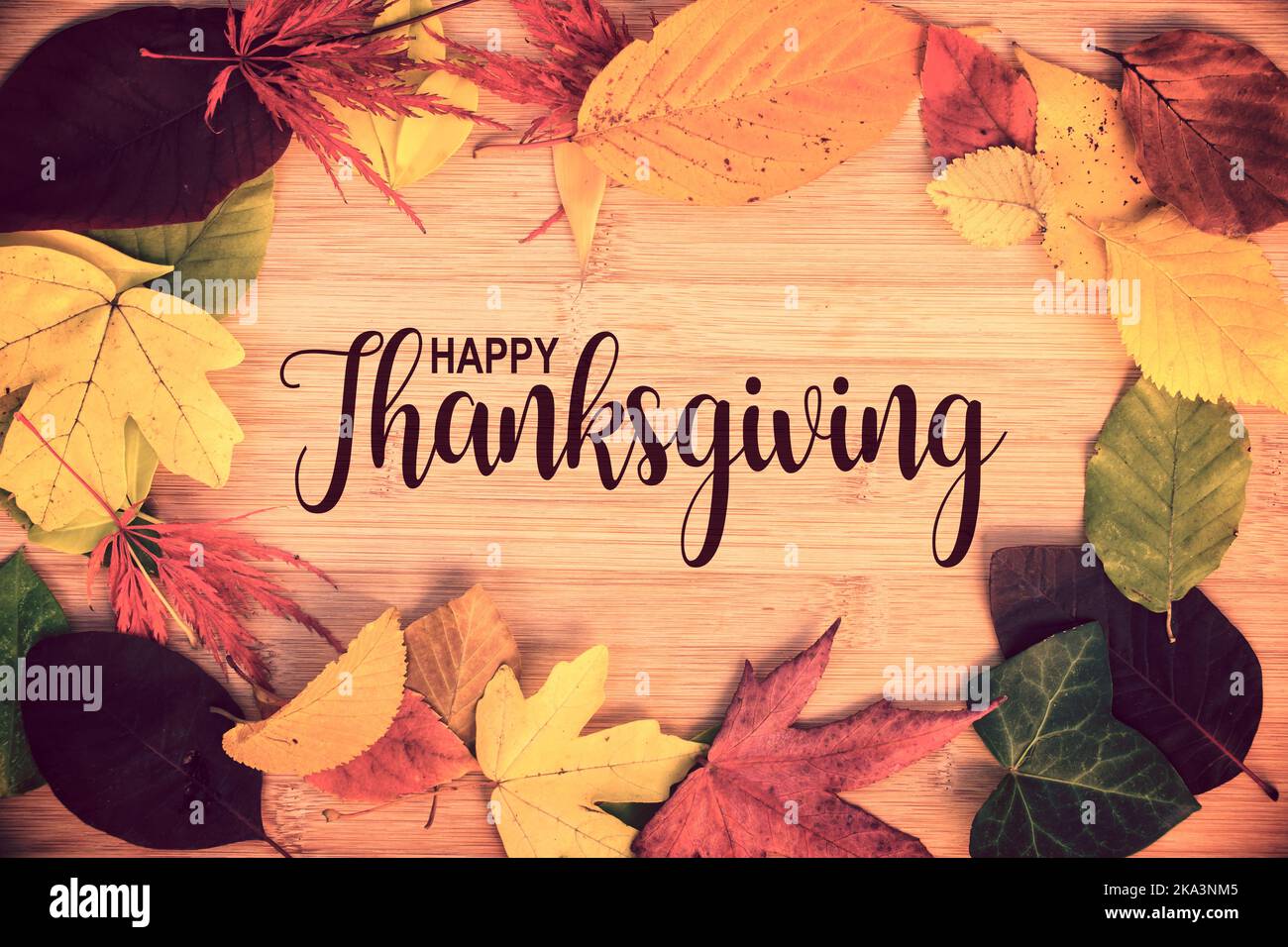 Happy Thanksgiving geschrieben in einem Rahmen von bunten Herbstblättern, Holzhintergrund Stockfoto