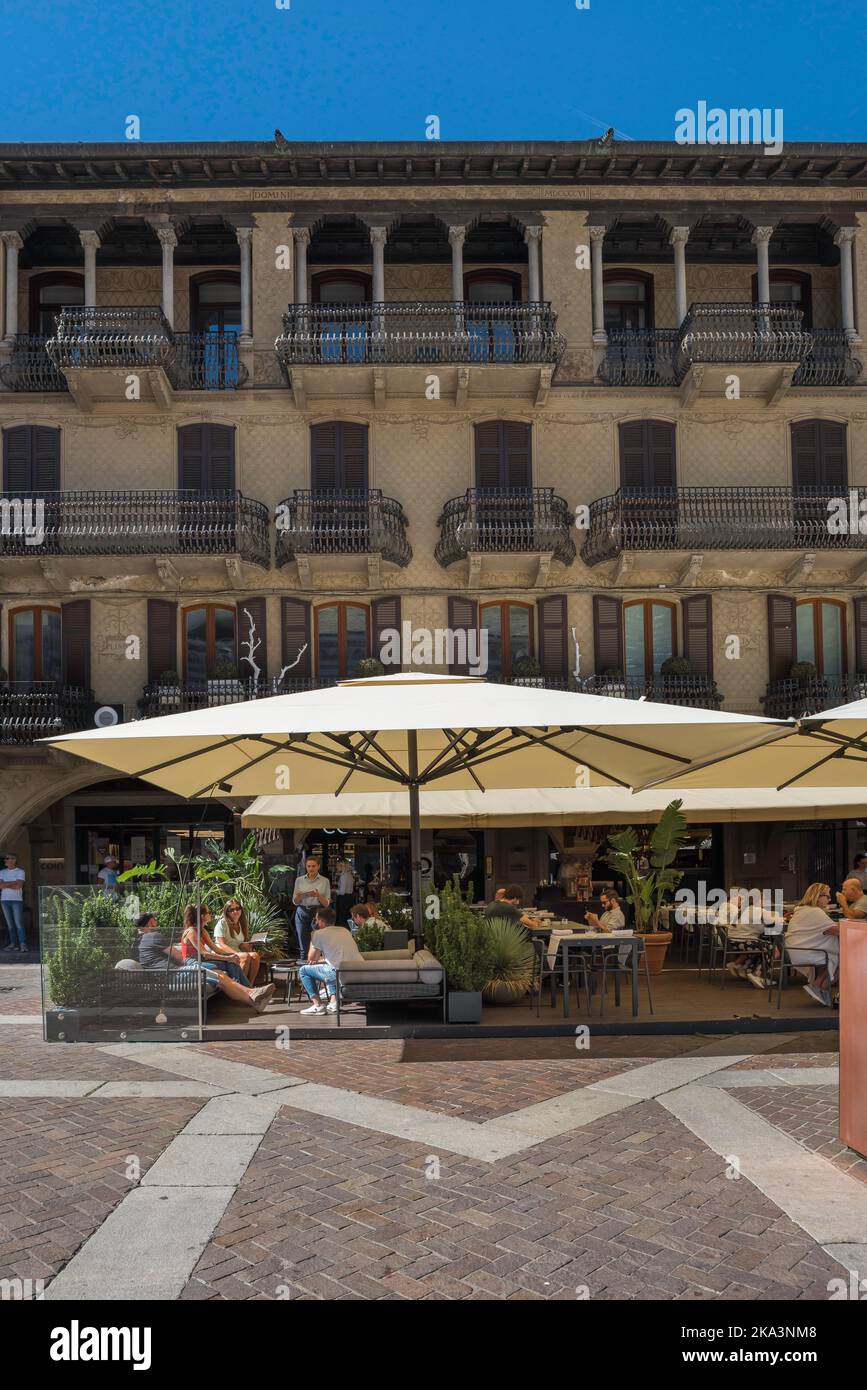 Bar für Jugendliche, Blick im Sommer auf eine Gruppe junger Menschen, die auf einer Café-Bar-Terrasse auf der Piazza Duomo im Zentrum der Stadt Como, Italien, sitzen Stockfoto