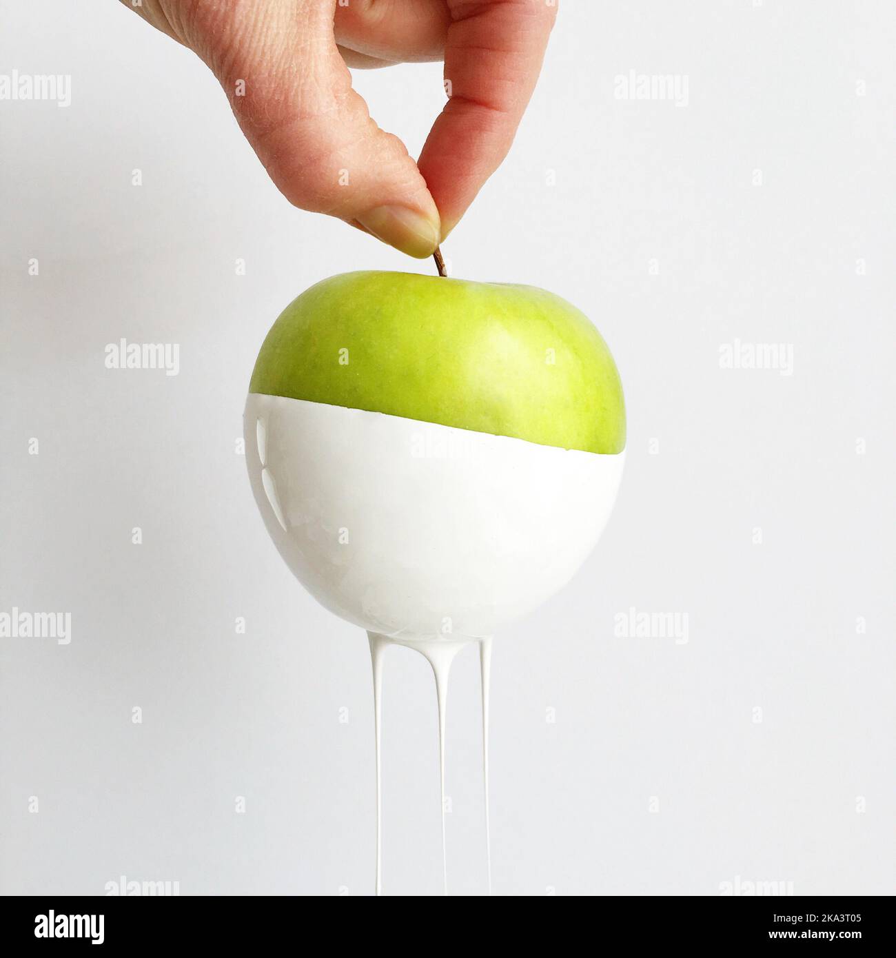 Nahaufnahme einer Hand mit einem grünen Apfel, der in Farbe getaucht und in den Hintergrund übergeht Stockfoto