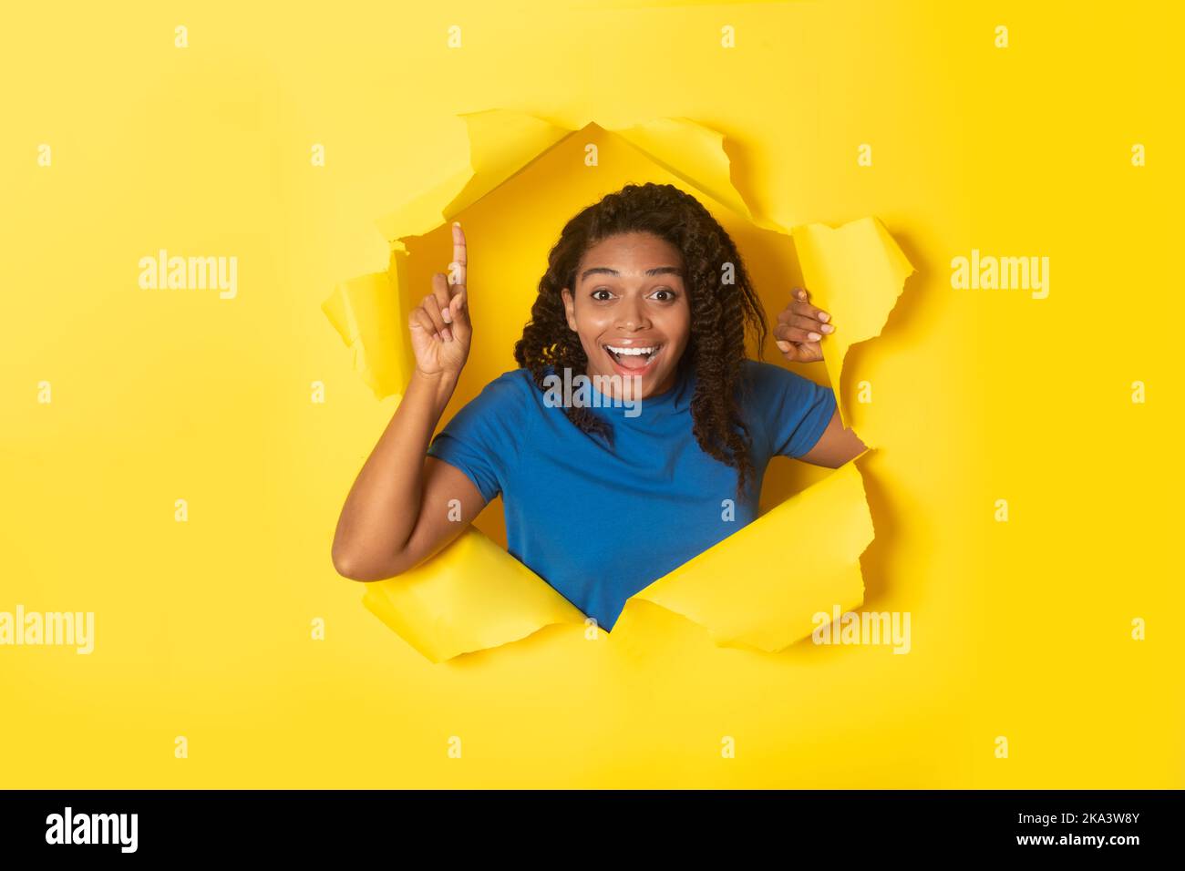 Aufgeregt Schwarze Frau Zeigt Finger Nach Oben Posiert In Zerrissenen Papier Stockfoto