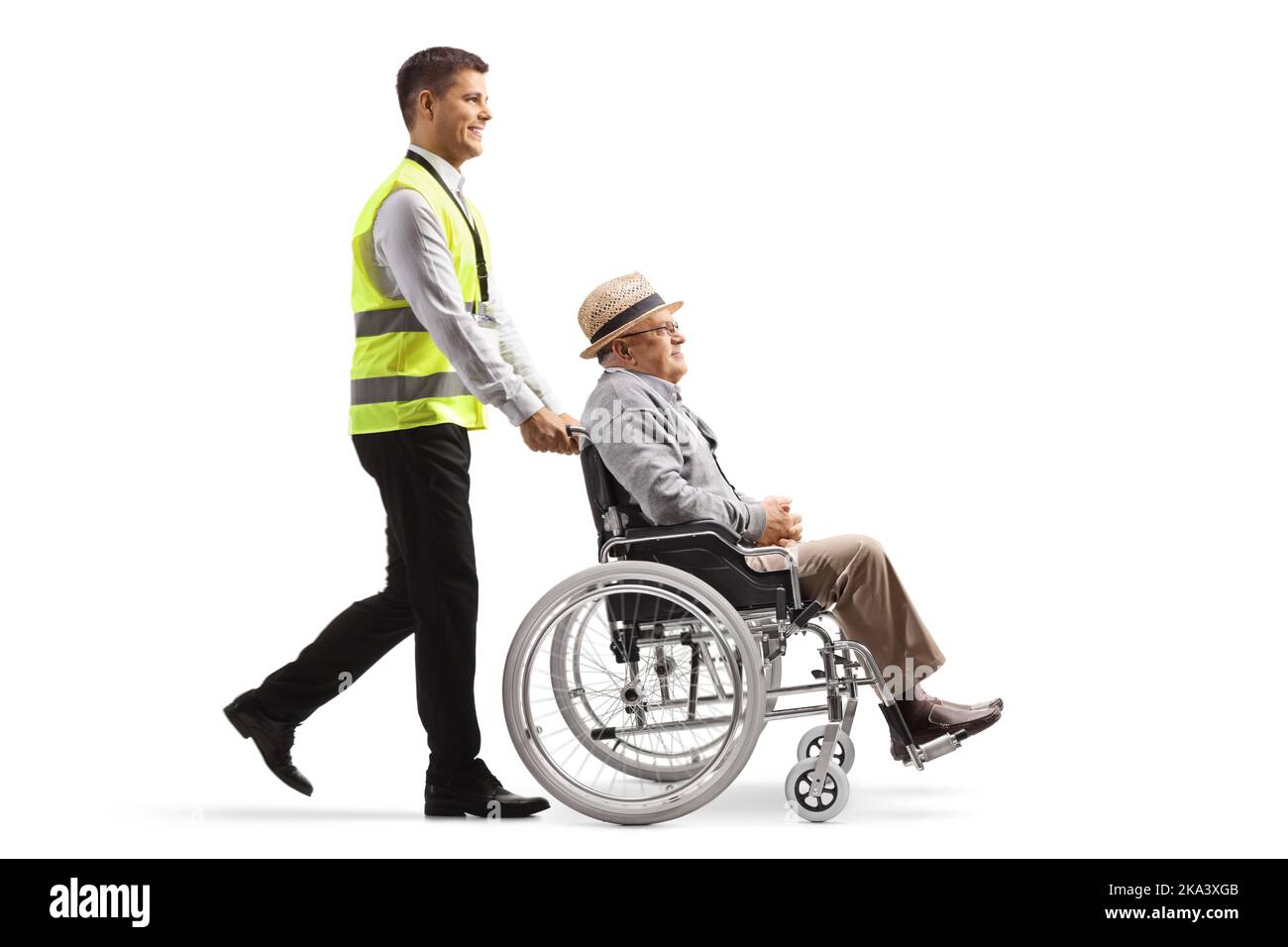 Ganzkörperaufnahme eines Flughafenarbeiters, der einen älteren Mann in einen Rollstuhl schiebt, isoliert auf weißem Hintergrund Stockfoto