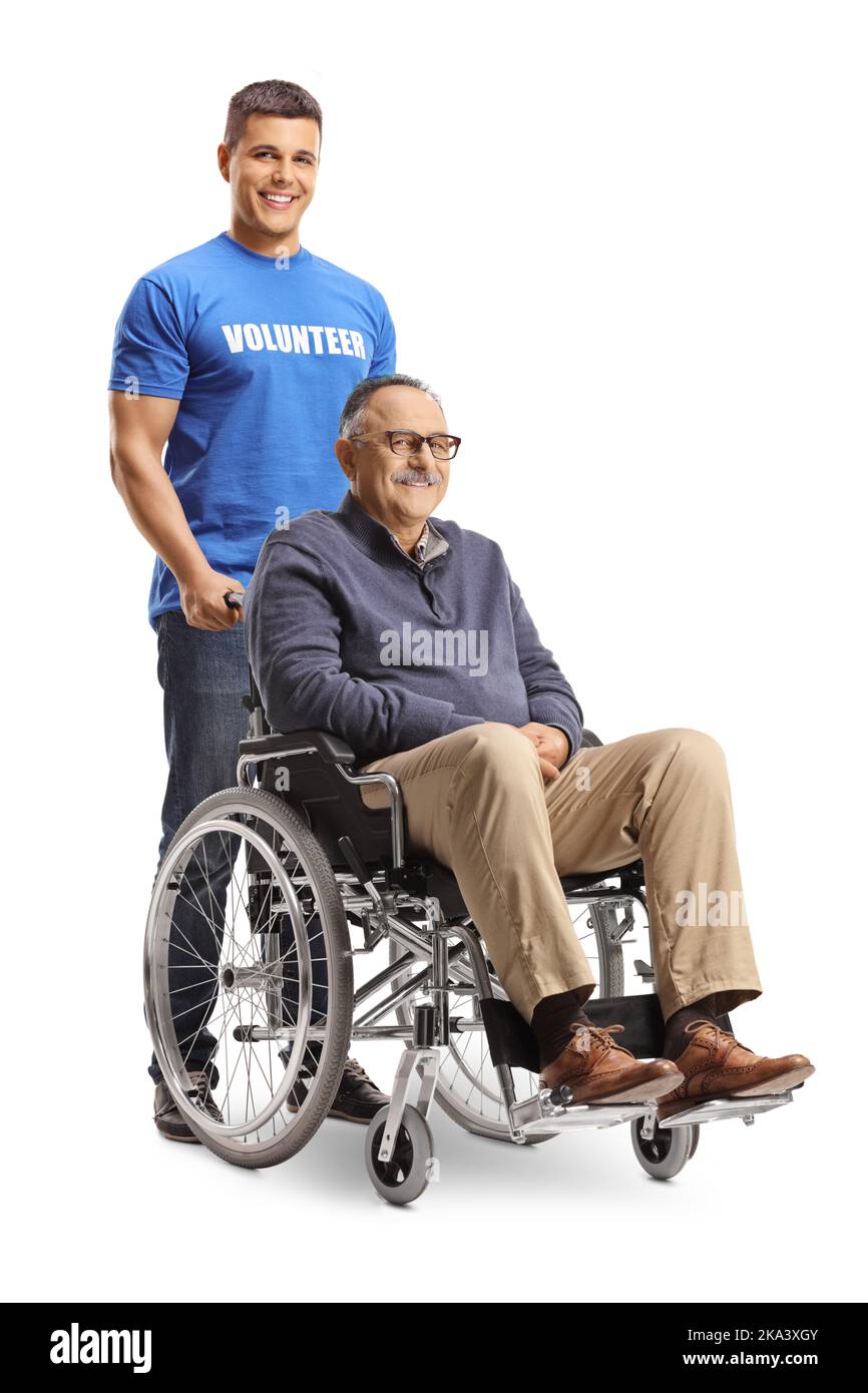 Junger männlicher Freiwilliger, der hinter einem reifen Mann steht, der in einem Rollstuhl auf weißem Hintergrund sitzt Stockfoto