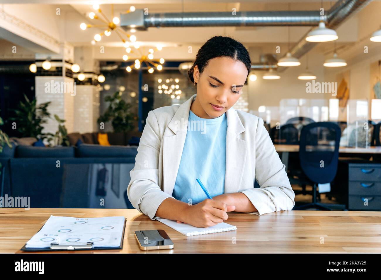 Fokussierte Frau macht Notizen. Mixed Race erfolgreiche Frau, Business-Mentorin, Finanzberaterin, Studentin, Schreiben von Informationen in Notebook während Online-Beratung oder Webinar per Videokonferenz Stockfoto
