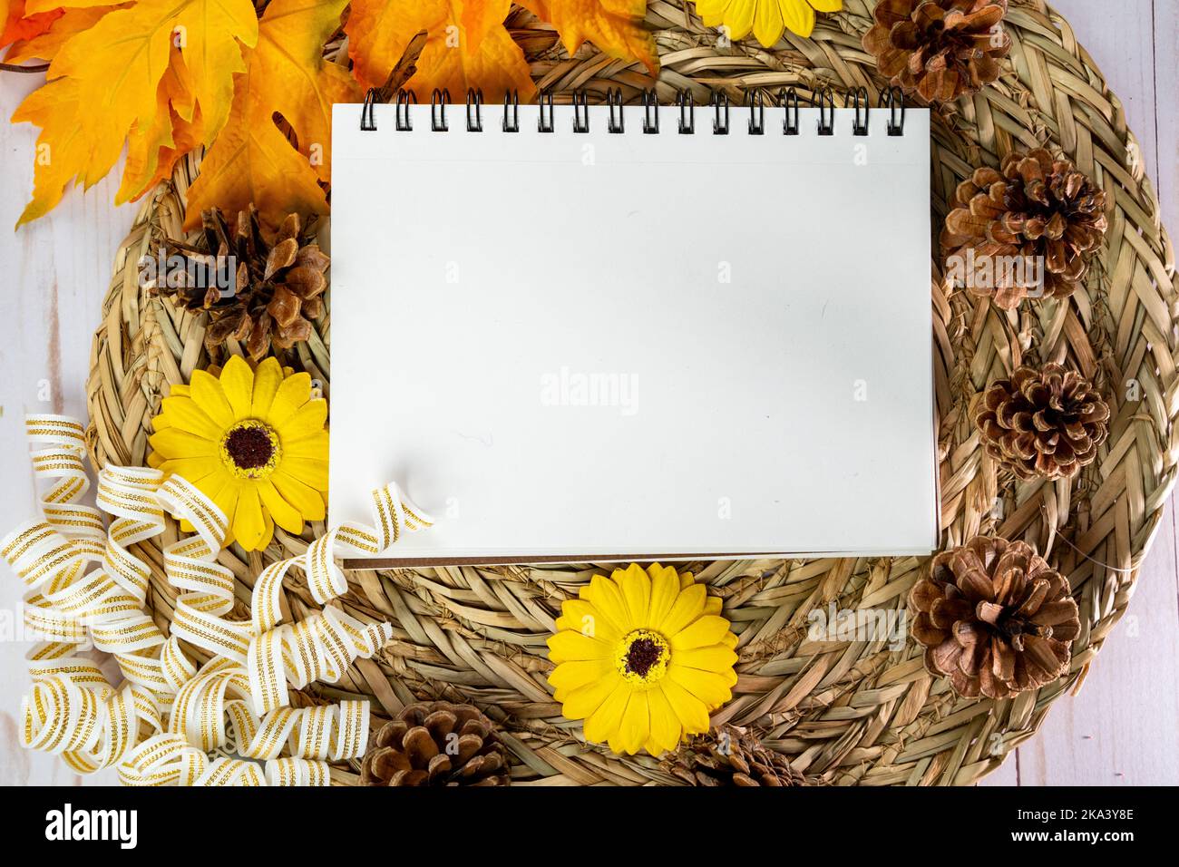 Flache, von oben nach unten gelegte Ansicht eines Notizbuches, Sonnenblumen und Ahornblätter Stockfoto