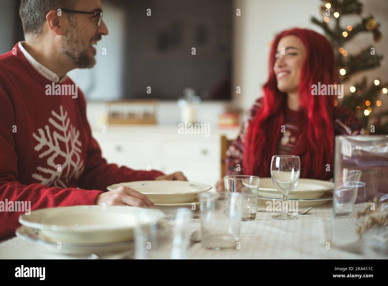 Mann, der mit seiner erwachsenen Tochter am Esstisch ein Weihnachtsfest sitzt Stockfoto