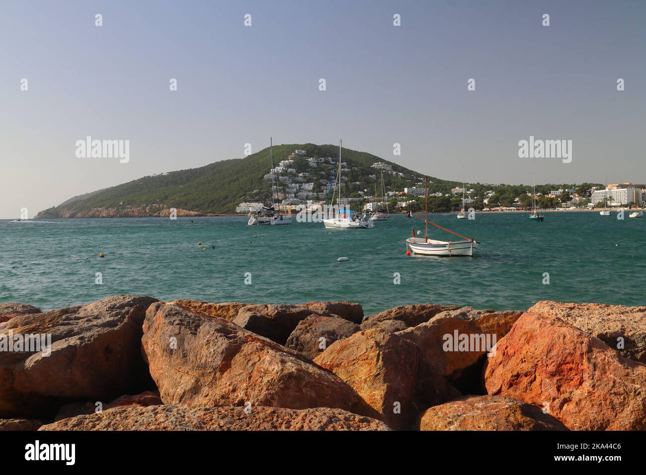 Blick auf den Hafen von Santa Eulalia mit den Sea Defense Felsen im Vordergrund. Ibiza, Balearen, Spanien. Stockfoto