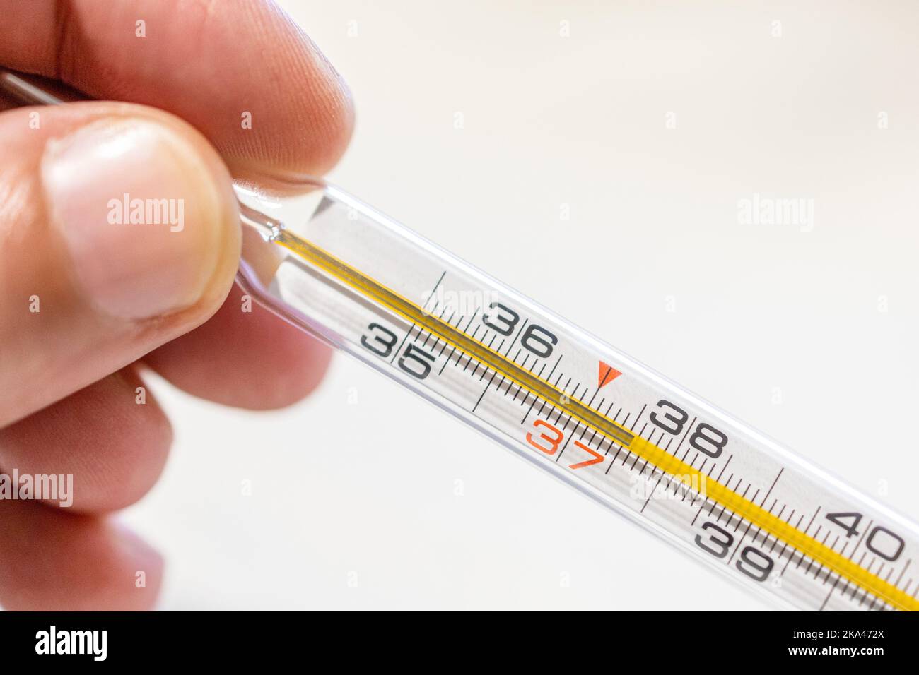 Die Hand hält das Thermometer, um die Temperatur bei 37,5 zu messen, sodass  es Fieber gibt Stockfotografie - Alamy