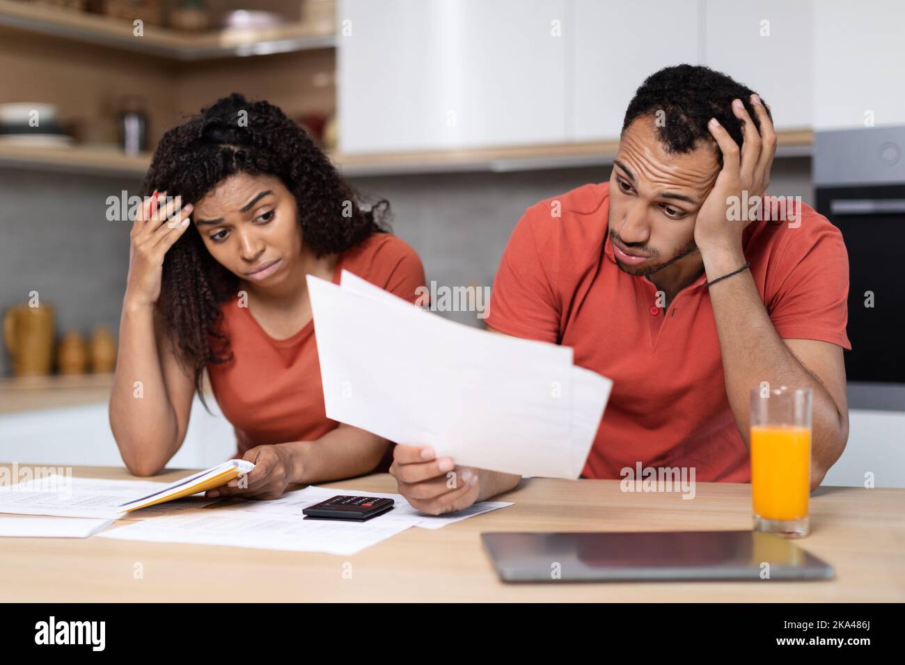 Traurige junge schwarze Paar arbeiten mit Dokumenten, pc, leiden unter Krise in der Küche Interieur Stockfoto