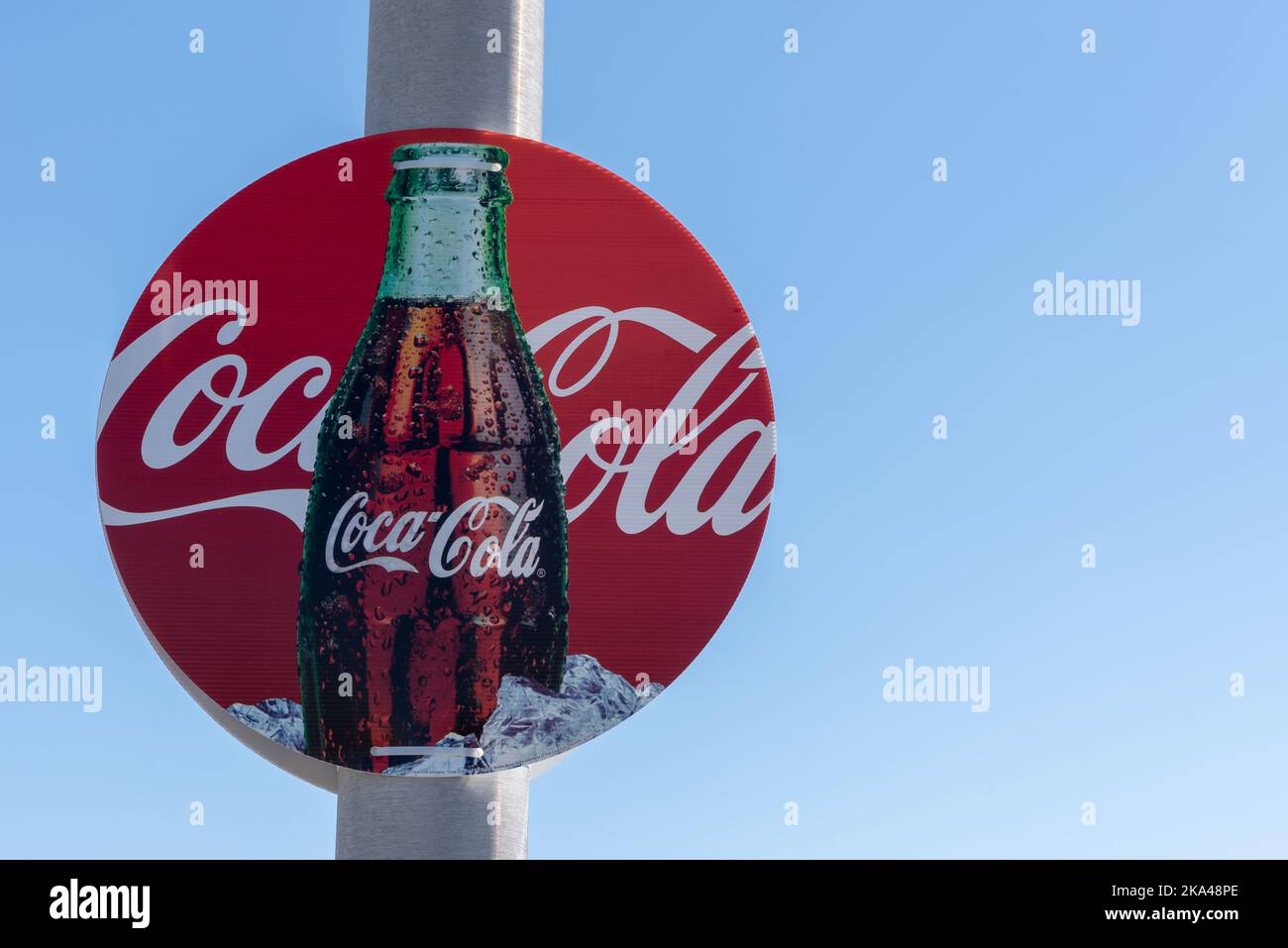 Ein rundes rotes Coca Cola-Schild, das eine offene Flasche Cola im Eis zeigt. Stockfoto