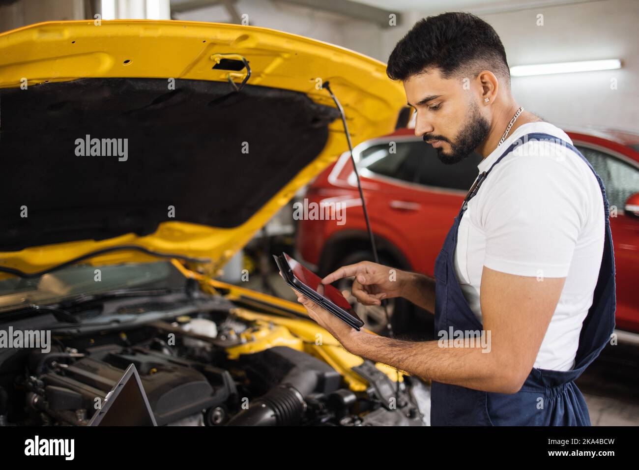 Serious fokussierten Mann Auto Techniker Mechaniker Reparatur Auto Problem des Motors, während der Systemprüfung Detail, mit Tablet-Computer für die Wartung und Befestigung in der Garage. Stockfoto