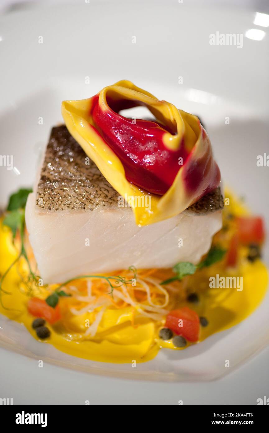 Weißer Fisch serviert mit einem gefüllten Tortellon auf einer gelben Creme Stockfoto
