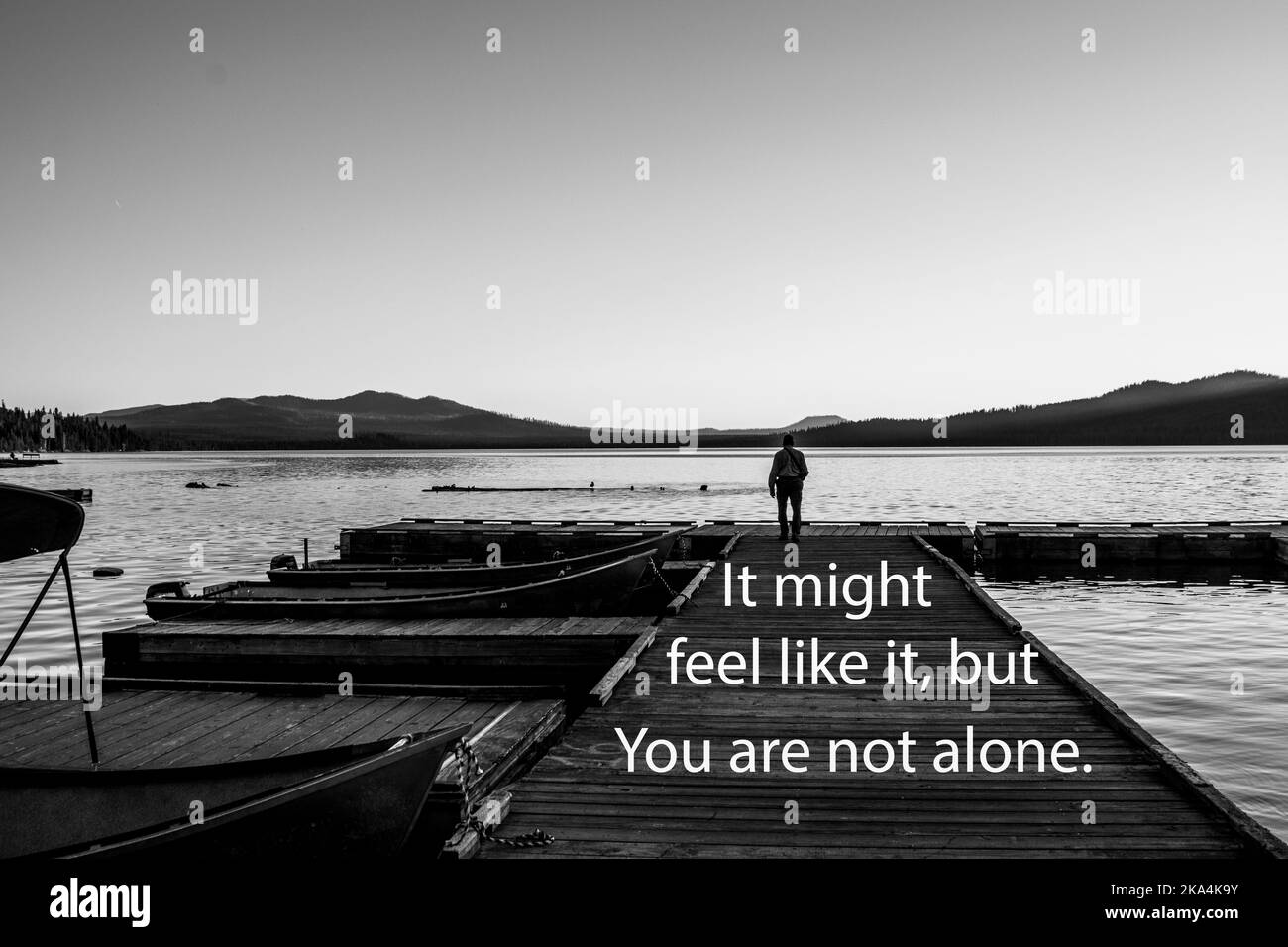 Schwarz-Weiß-Bild einer Person allein auf einem Holzdock, mit SMS-Nachricht "wenn könnte das Gefühl, wie es, aber Sie sind nicht allein. Stockfoto