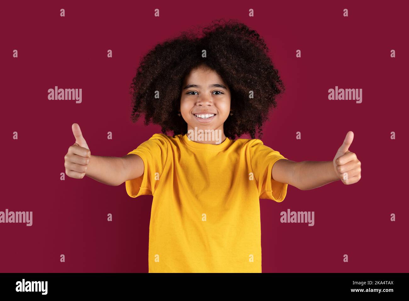 Fröhliche afroamerikanische Mädchen zeigt Daumen nach ups, isoliert Stockfoto