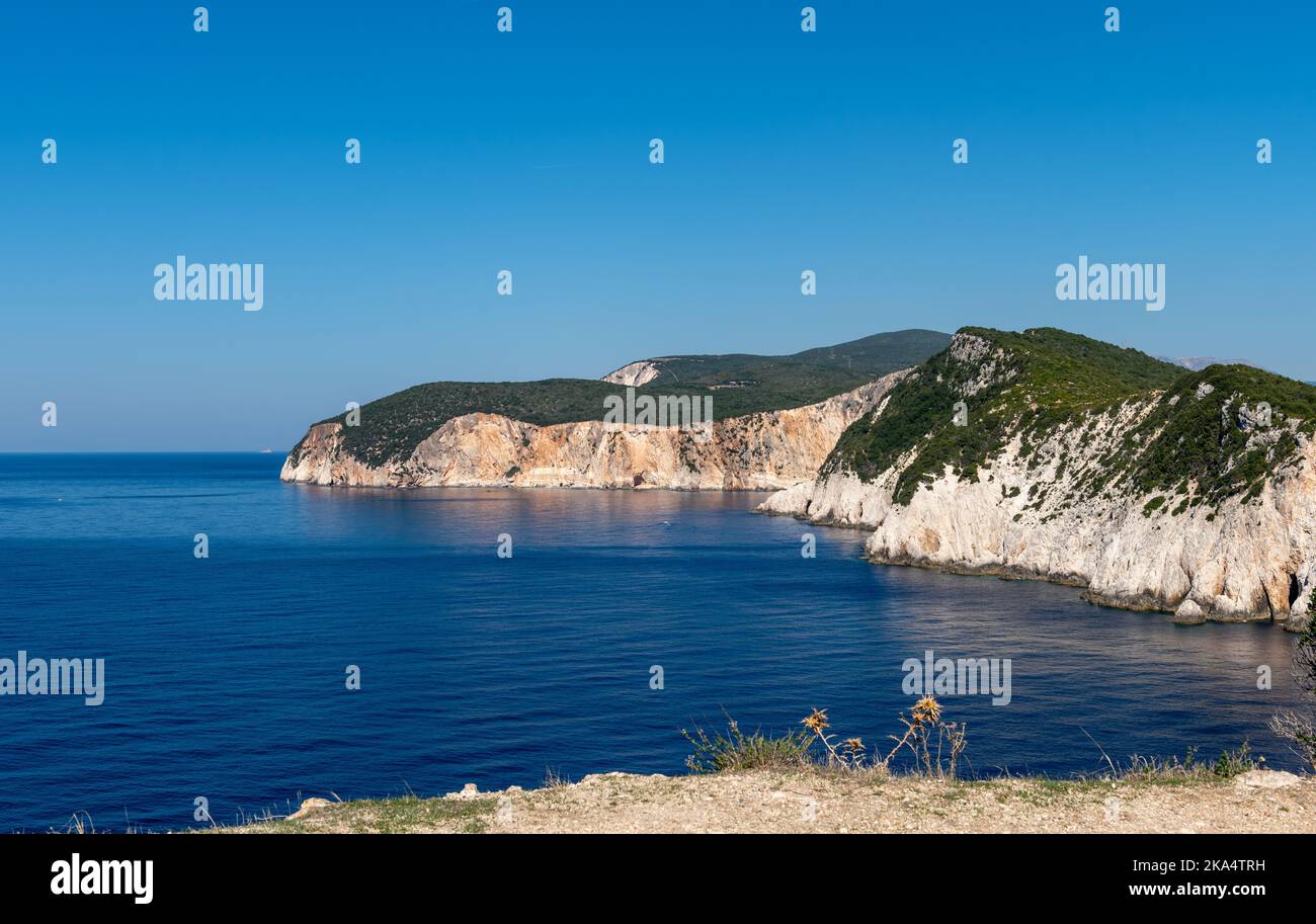 An einem schönen, wolkenlosen Tag mit blauem Himmel gleiten die Felsklippen der Landzunge in das tiefblaue Meer. Stockfoto